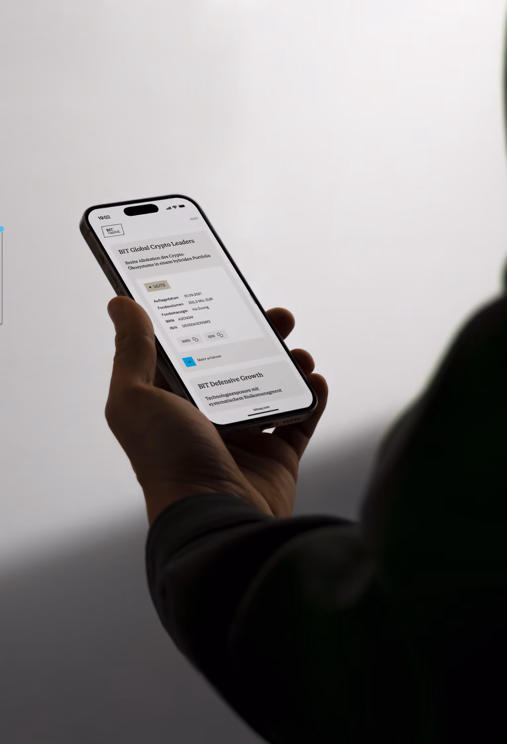 Person holding a smartphone displaying BIT Global Crypto Leaders investment information on screen.