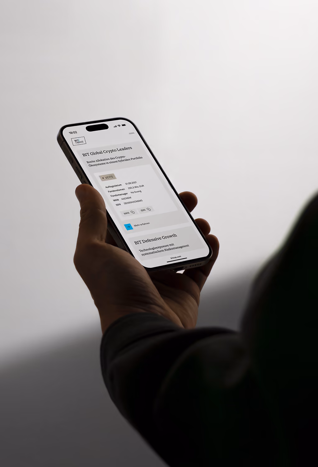 Person holding a smartphone displaying BIT Global Crypto Leaders investment information on screen.