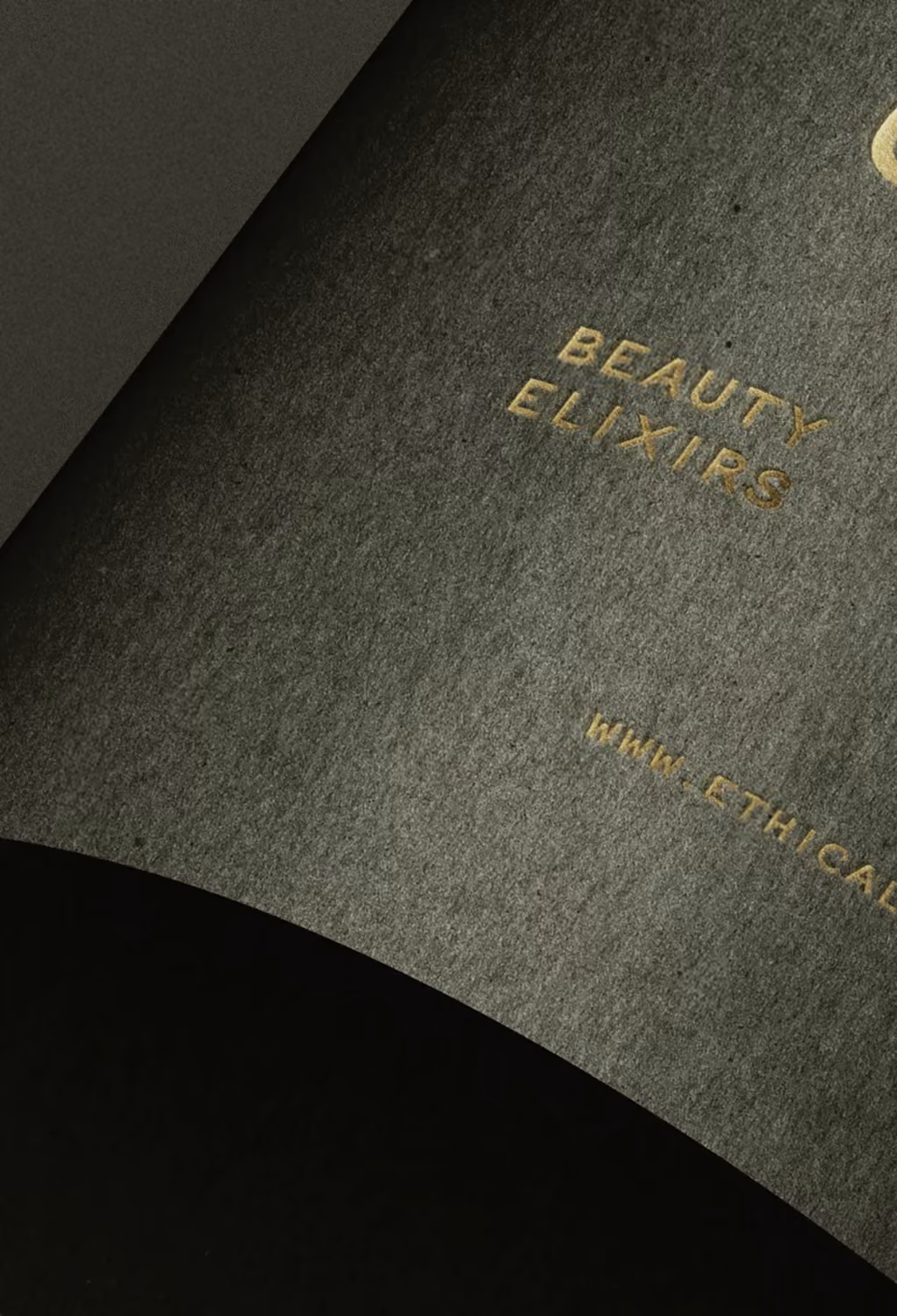 Close-up of textured dark gray paper with gold embossed text 'Beauty Elixirs'.
