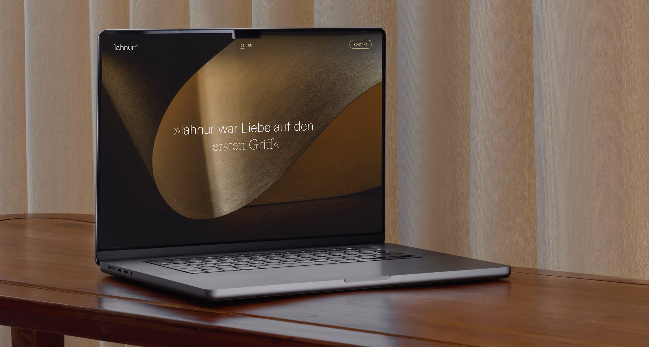 Open laptop on wooden table displaying abstract brown satin texture with German text.