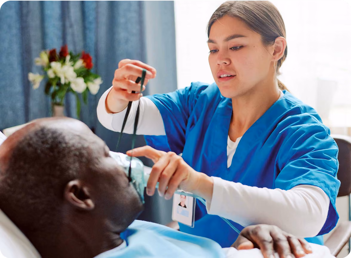 a woman wearing blue scrubs holding a stethoscope to a man's face