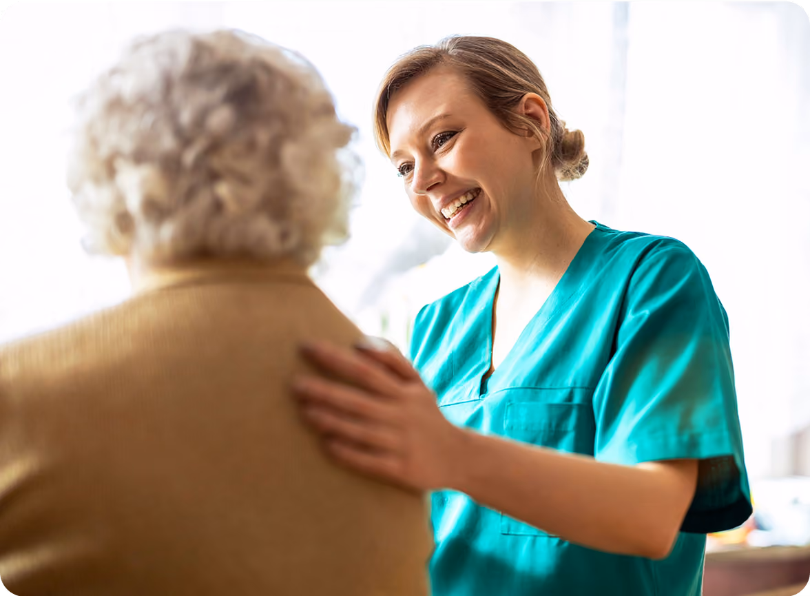 a woman in green scrubs hugging an old woman