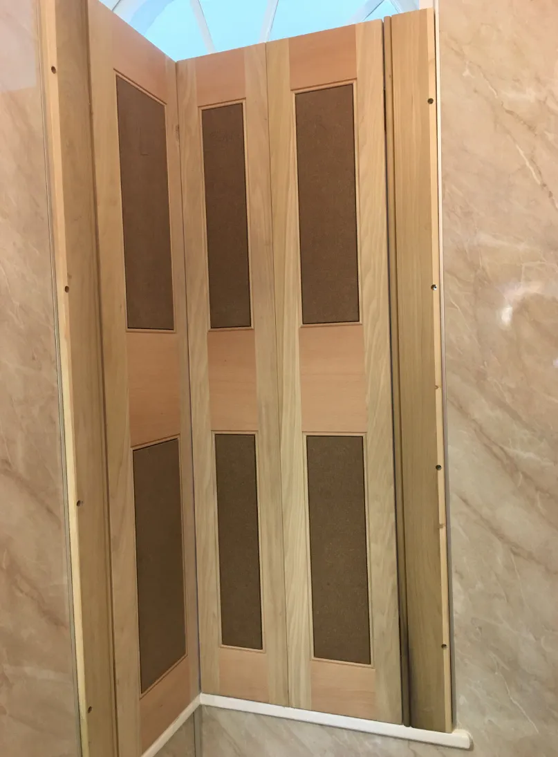 Wooden folding window shutter with rectangular panels in a beige marble wall.