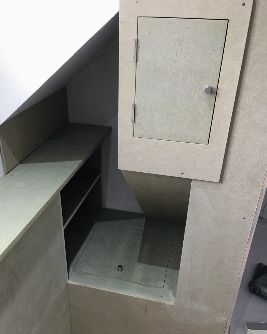 Open empty cream kitchen cabinet mounted on a wall above a marble backsplash.