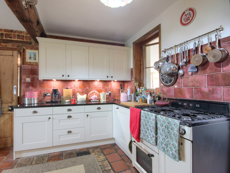 Modern white kitchen wall with built-in double oven and open refrigerator filled with food and drinks.