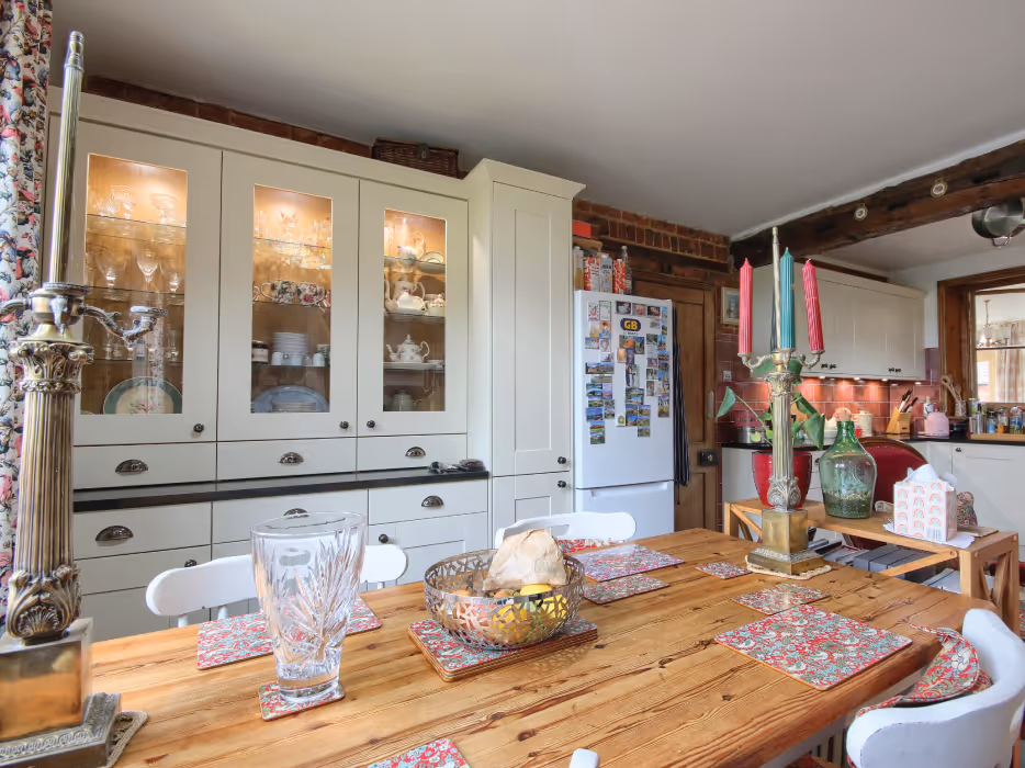 Modern white kitchen wall with built-in double oven and open refrigerator filled with food and drinks.