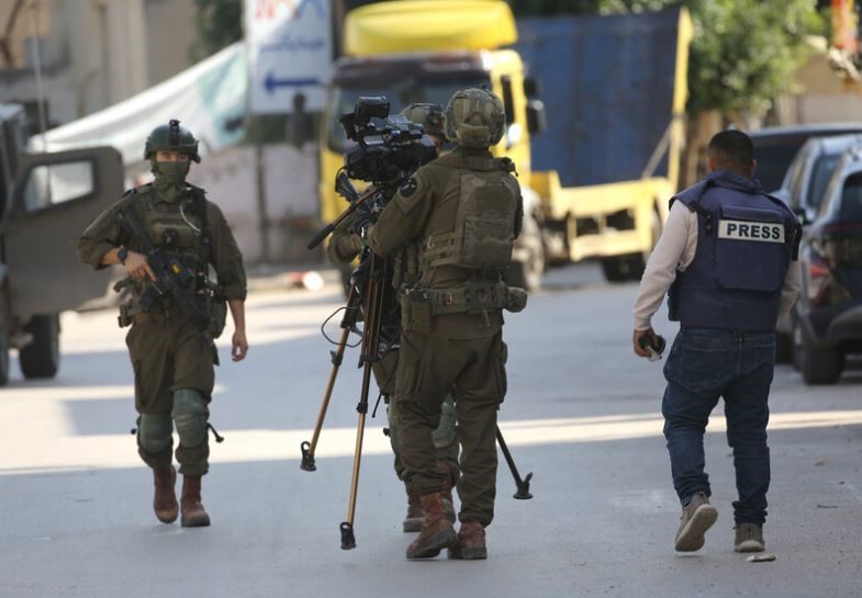 IDF Troops confiscating a West Bank Journalist's equipment (Image IFJ)