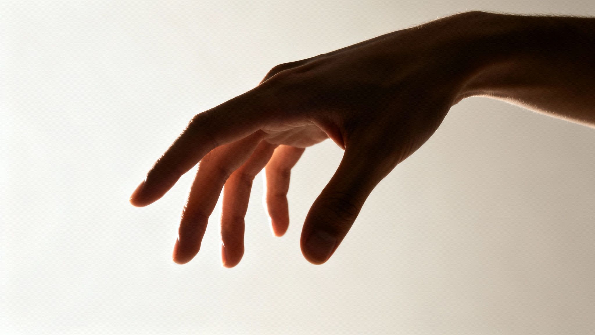 A human hand, silhouetted against a bright background, reaching down with fingers slightly spread.