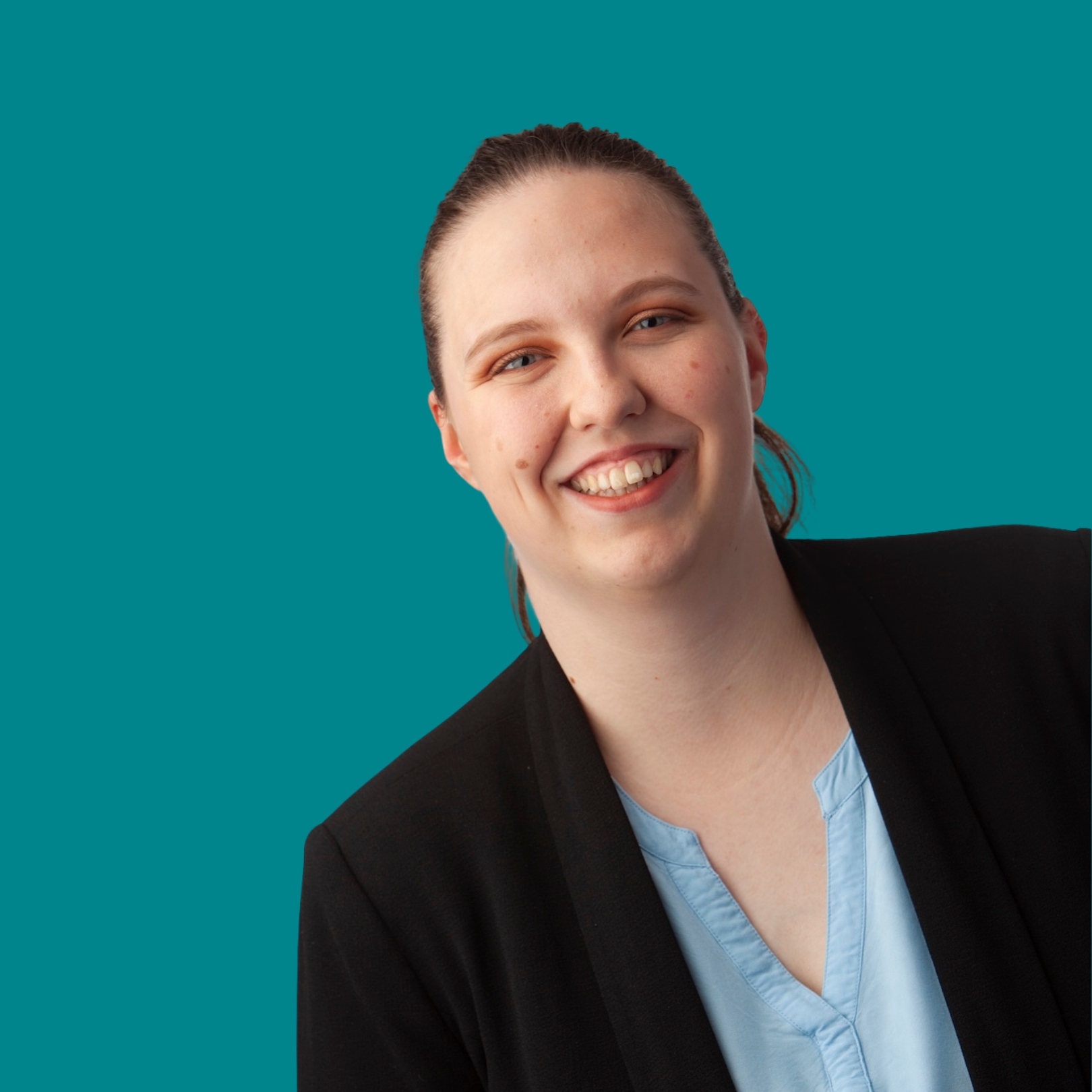 Porträt einer freundlichen Frau, die ein blaues Shirt und einen schwarzen Blazer trägt. Der Hintergrund ist türkis.