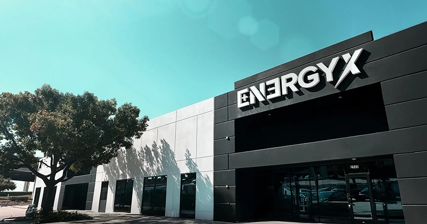 Low-angle exterior shot of the EnergyX headquarters, a modern two-story building with a black and white facade under a clear sky.