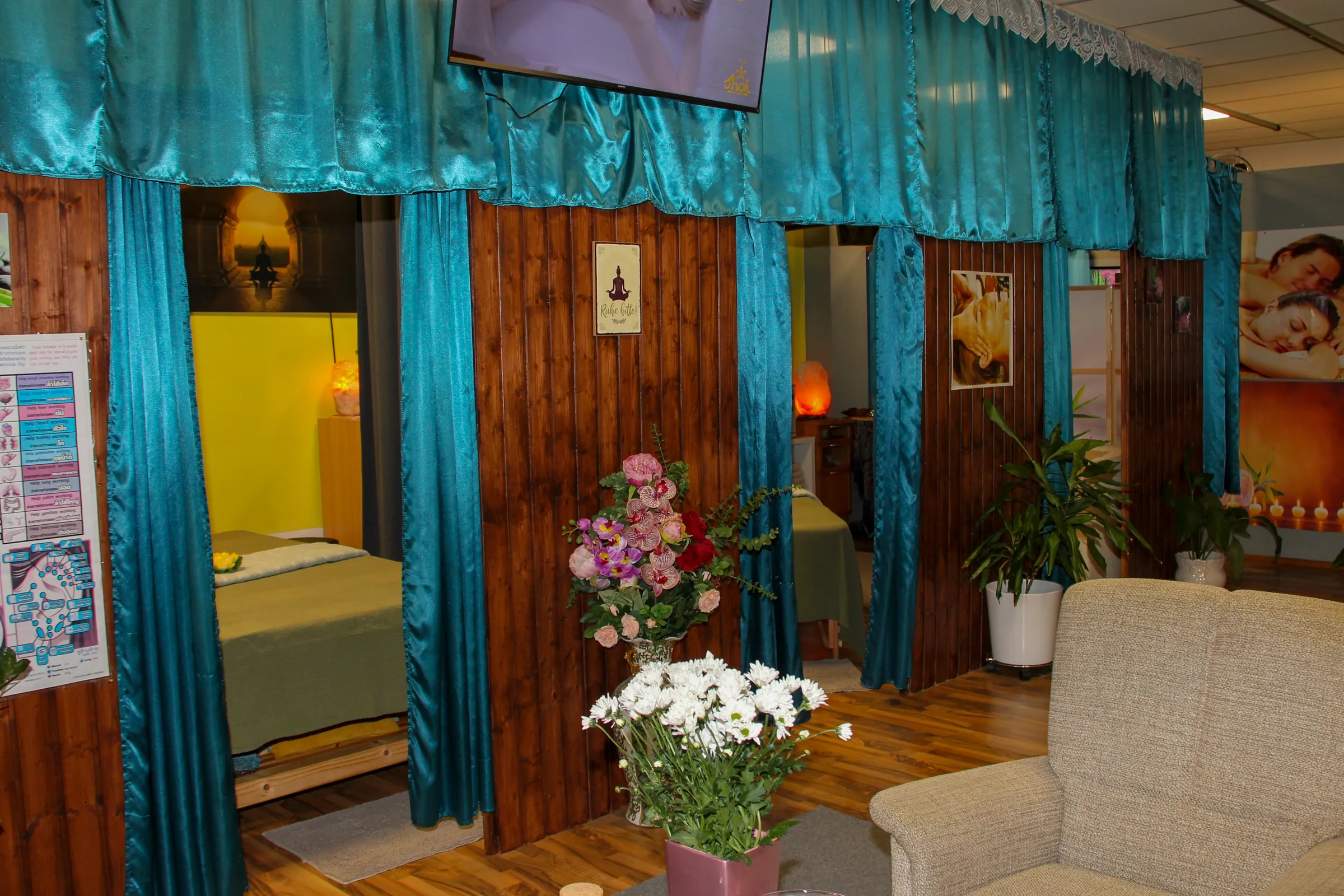 Behandlungskabinen mit türkisfarbenen Vorhängen, Pflanzen und Sitzecke bei BIU Thai Massage Kelheim