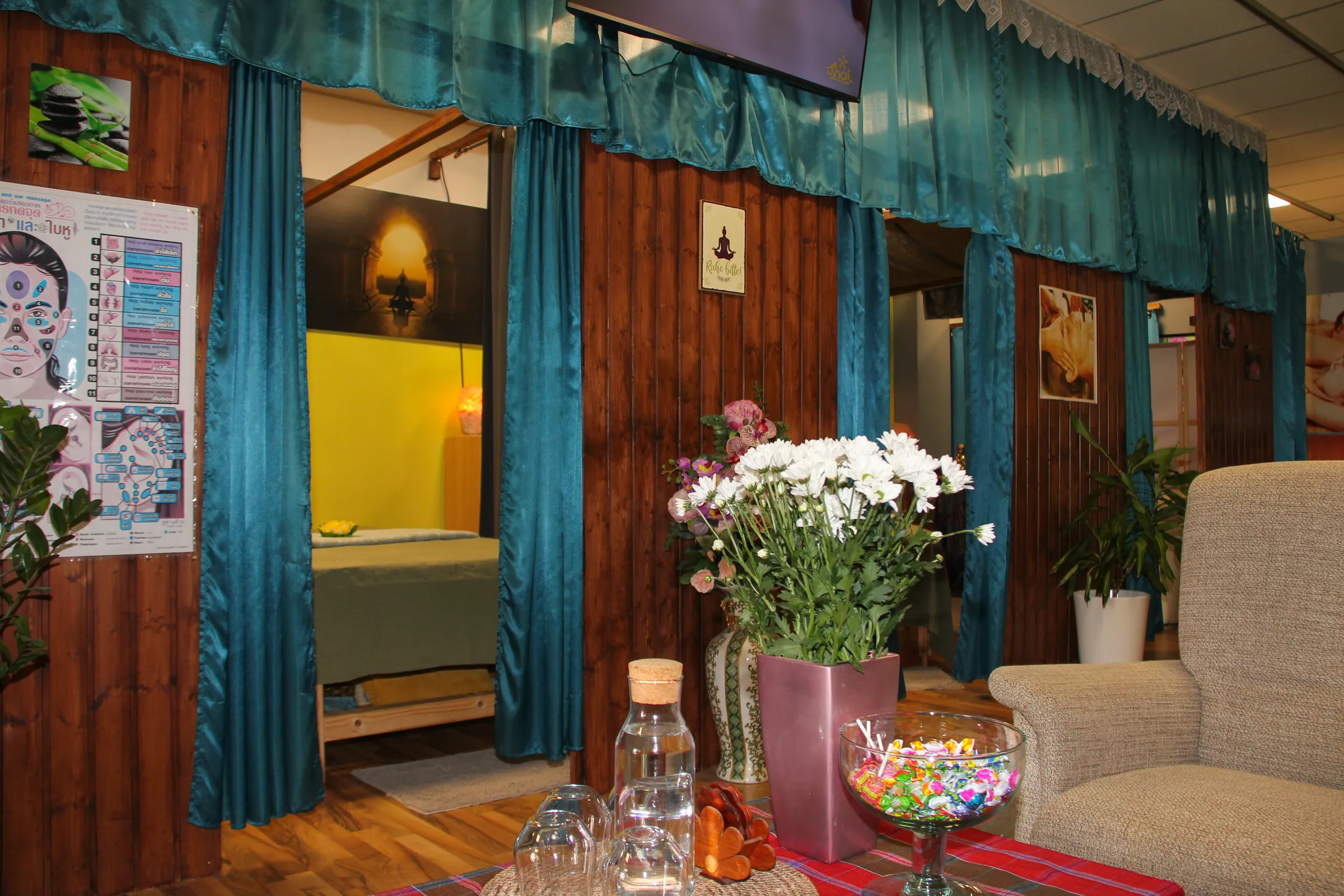 Behandlungskabine mit Vorhang, Blumen und Sitzbereich im Thai-Massage-Salon Kelheim