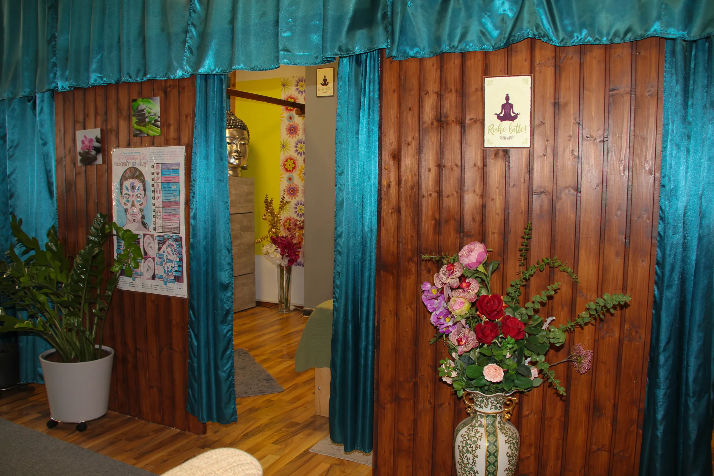 Behandlungskabine mit Holzwand, Vorhang und Blumenstrauß im Thai-Massage-Salon Kelheim