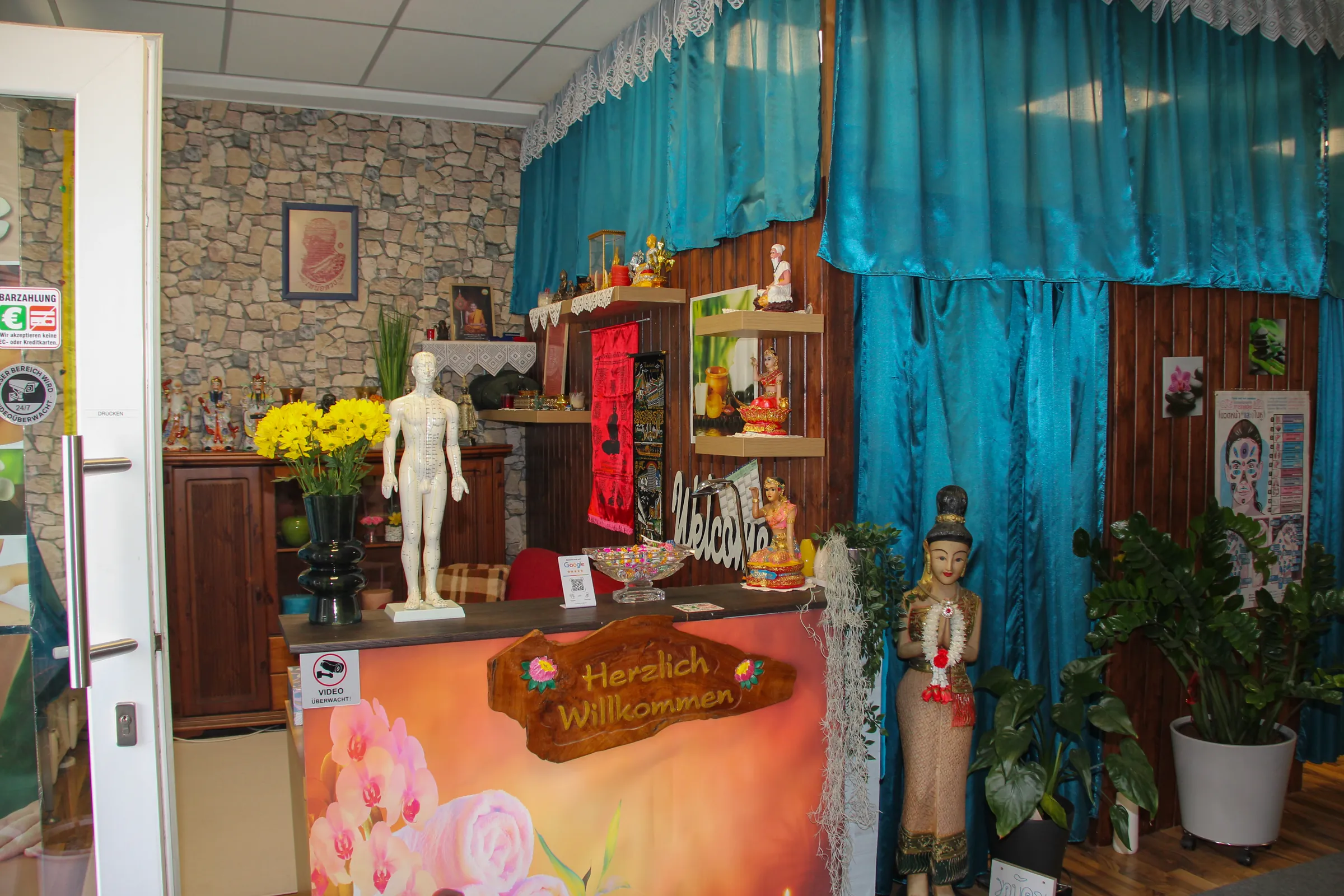 Empfangstheke mit „Herzlich Willkommen“-Schild und thailändischer Dekoration bei BIU Thai Massage Kelheim