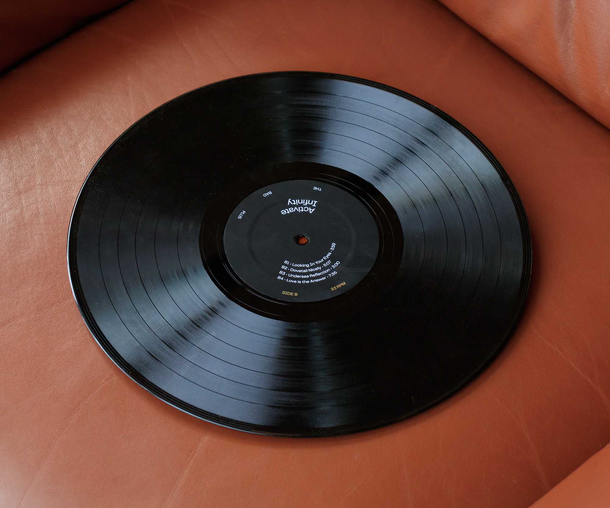 Vinyl record on a leather sofa. The label lists the B-Side tracks, arranged in a circle around the center spindle hole.
