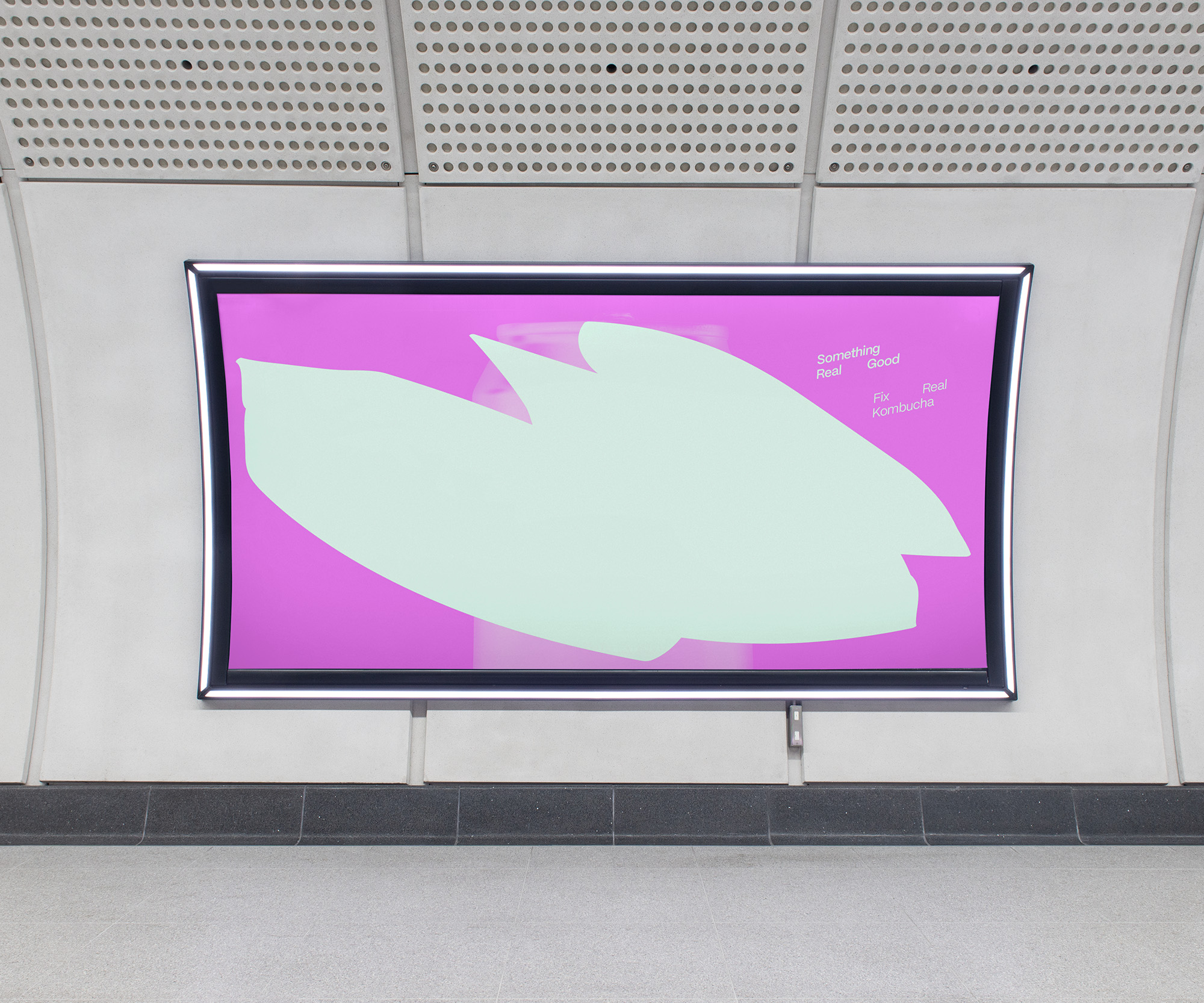 A bright pink horizontal advertisement in an Elizabeth Line station. A semi-transparent image of a drink can is obscured by a wide, pale green organic shape. Diagonal, slanted text in the top-right corner reads “Something Real Good”, followed by “Fix Kombucha”.