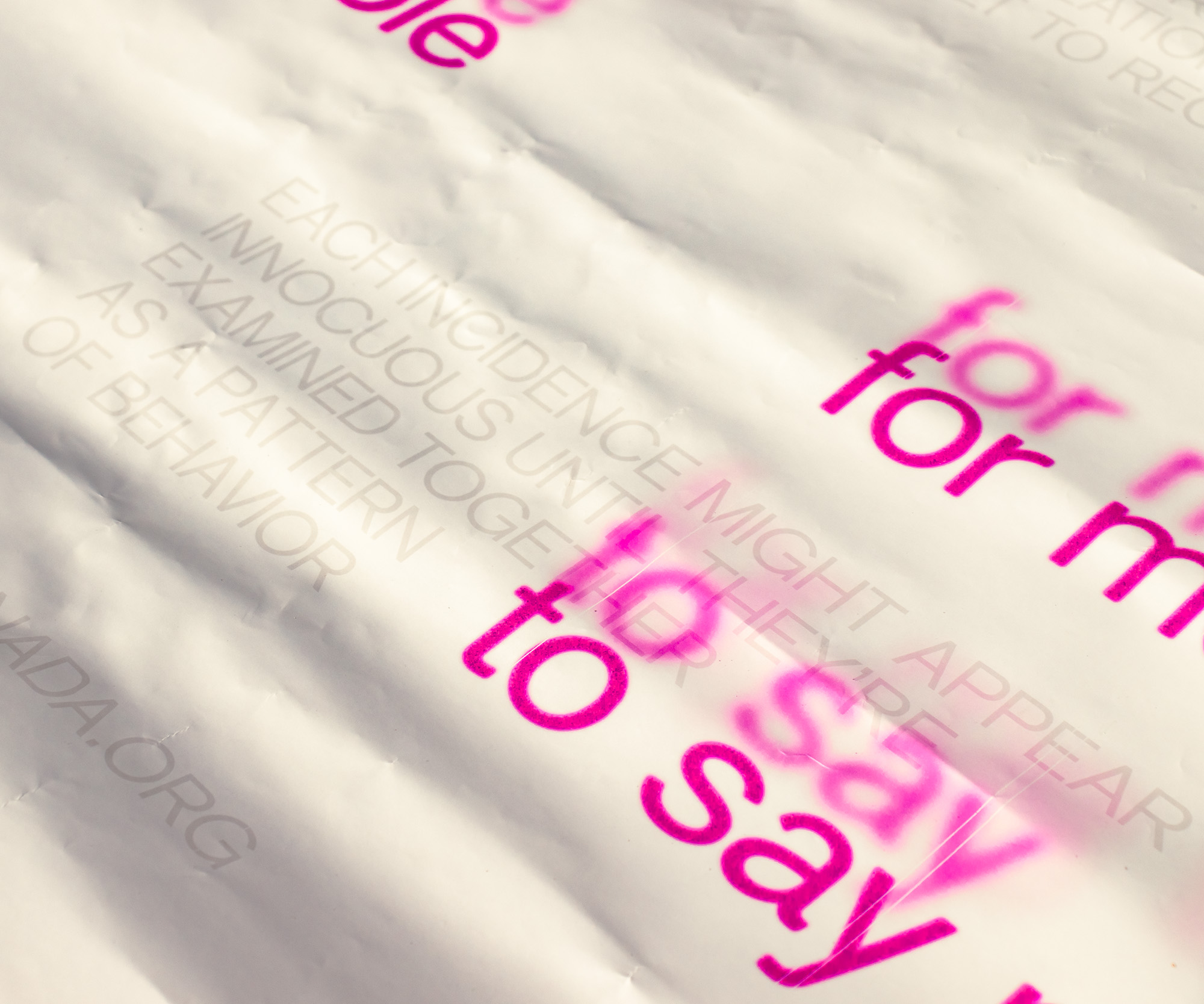 Closeup of the lower-right center of the poster. Pale text reads “Each incidence might appear innocuous until they’re examined together as a pattern of behaviour”.