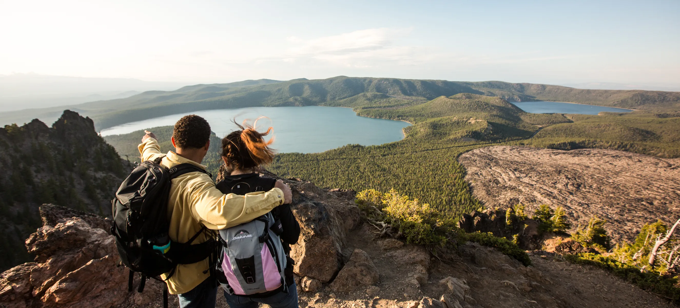 A man and a woman standing on top of a mountain.