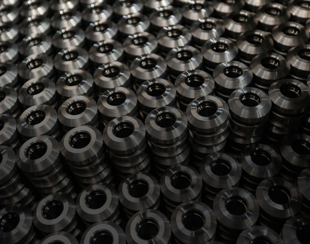 Stacks of identical cylindrical metal parts with central holes arranged in a tightly packed pattern.