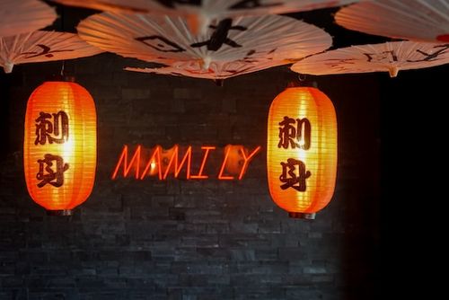 Photo d'un restaurant japonais avec une décoration 100% noire sol mur plafond, lumière tapisée, lanternes rouges en papier et parapluie en papier de riz au plafond.