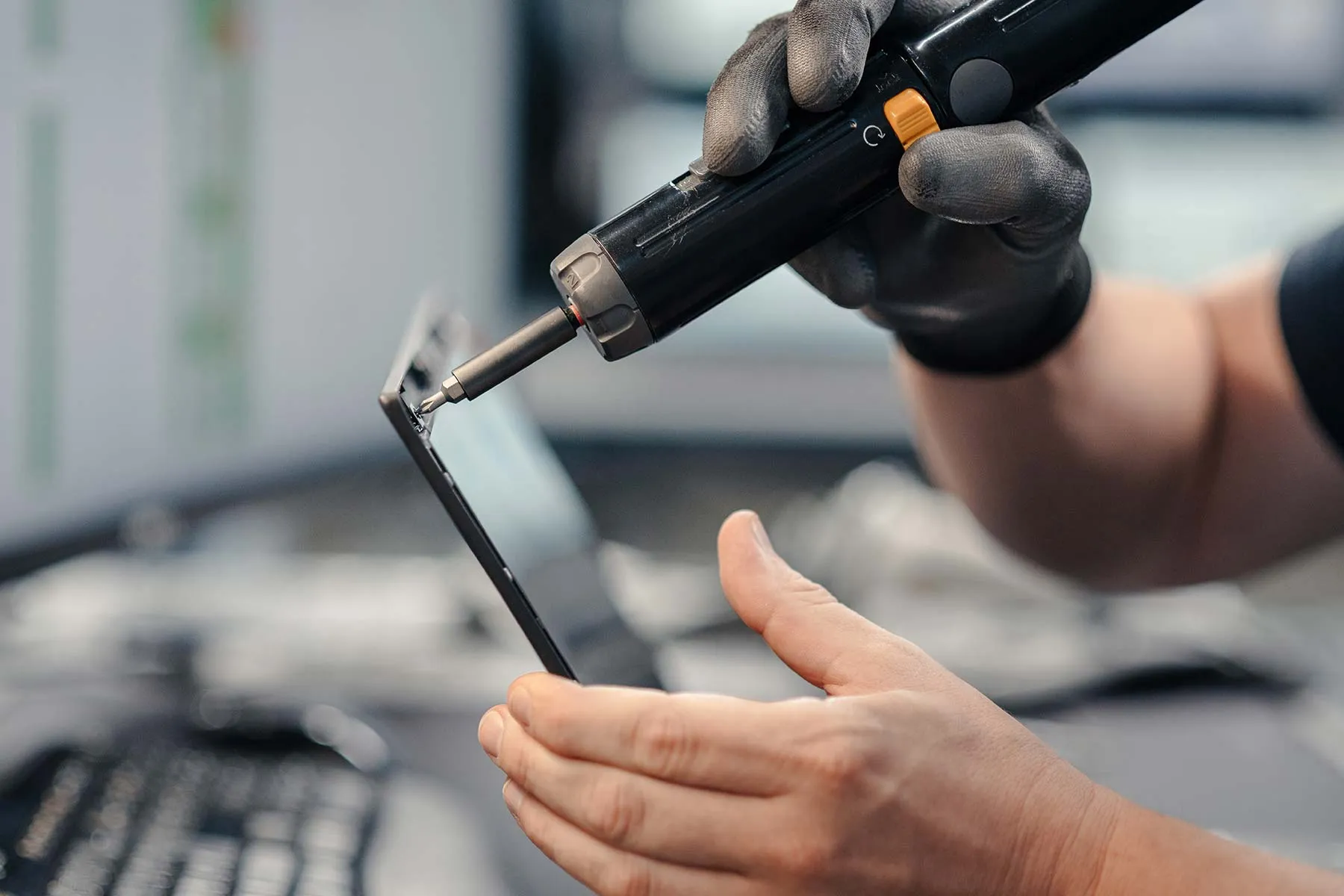Ein Mitarbeitender schraubt an einem Smartphone