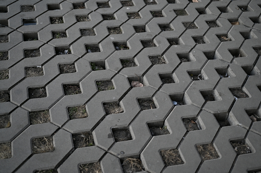 Interlocking concrete grass pavers with gaps filled by soil and dry grass
