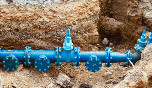 Blue water main with flanged valves exposed in an excavated trench