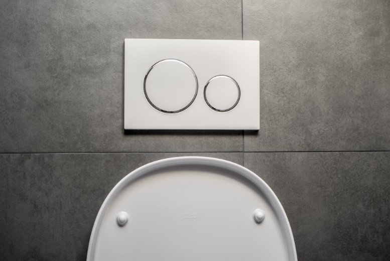 White wall-hung toilet with a dual flush plate on grey tiles above the seat