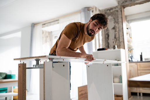 Man assembling a white flat pack table in a bright living room