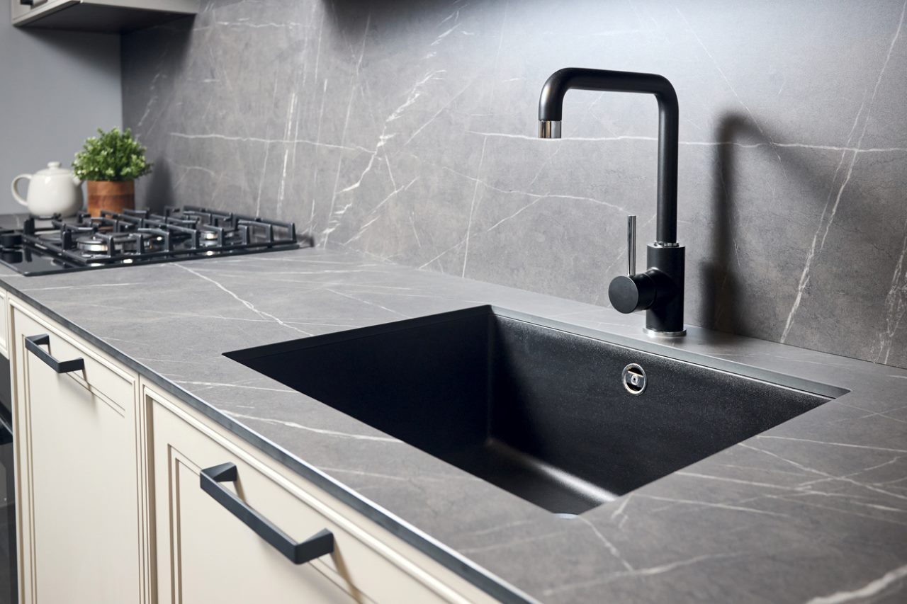 Black undermount kitchen sink with a black mixer tap in a grey marble-effect worktop