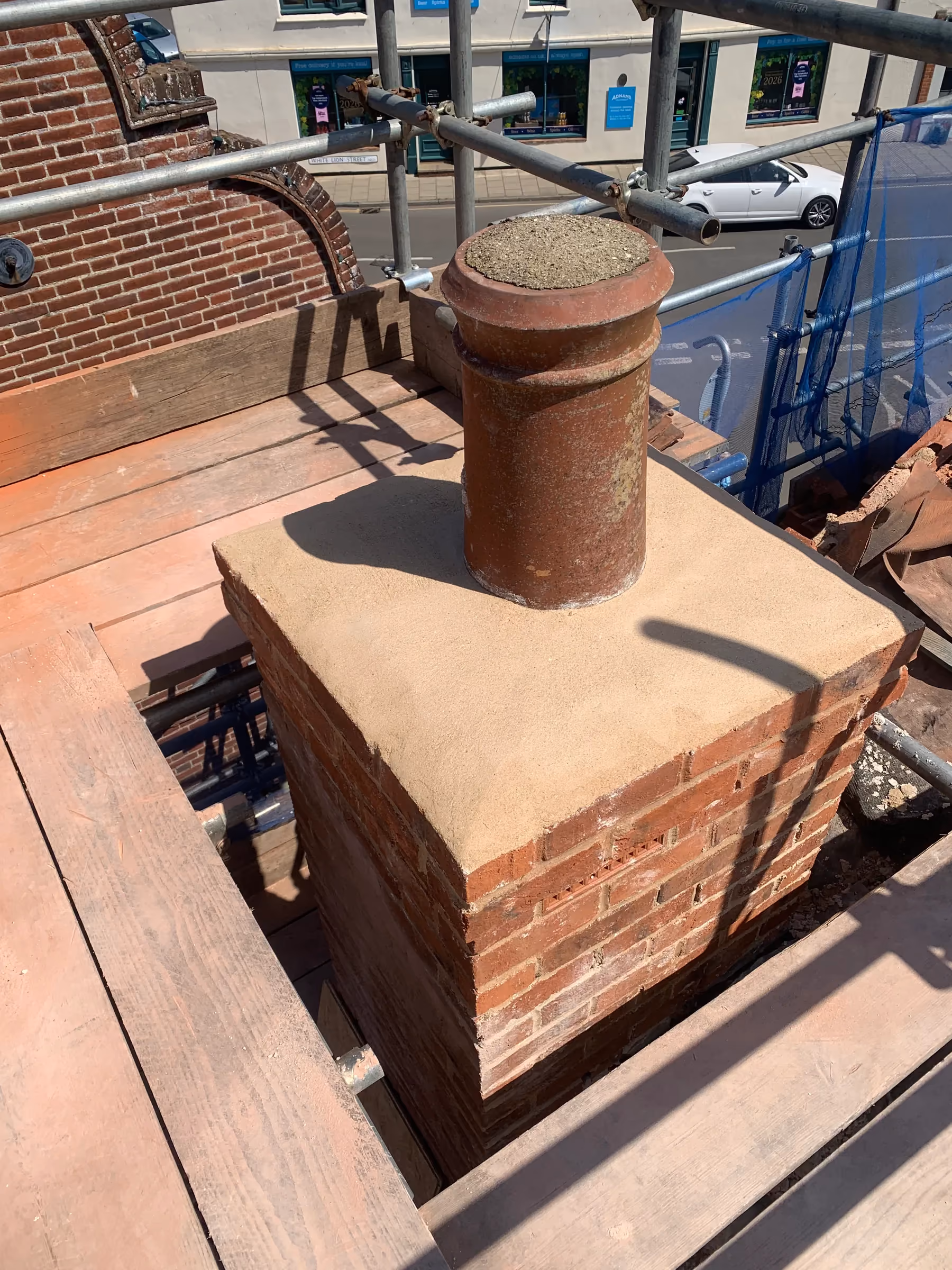 Rebuilt chimney in exposed brick and lime mortar with the original pot reinstated
