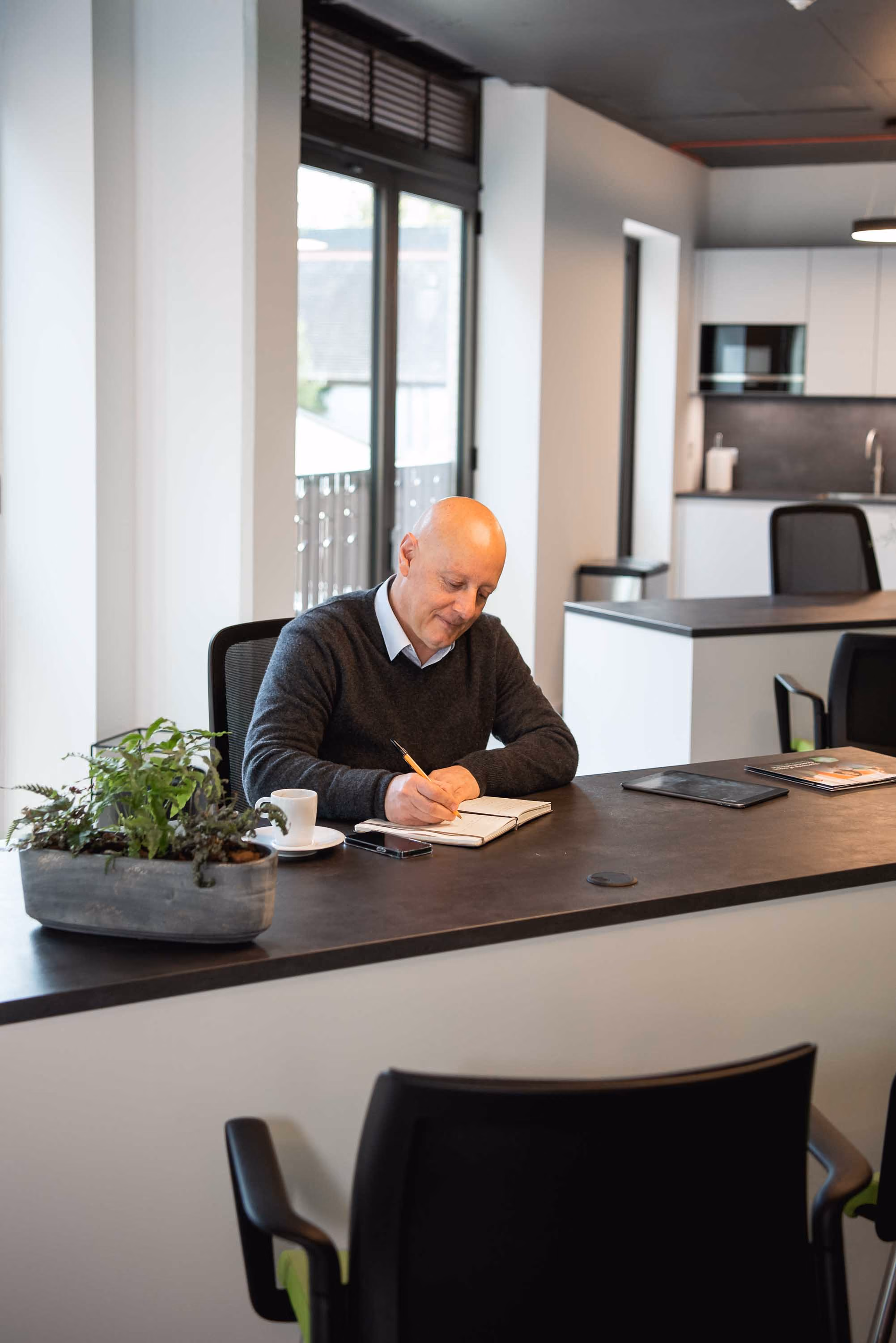 A man sitting at a table writing on a piece of paper.