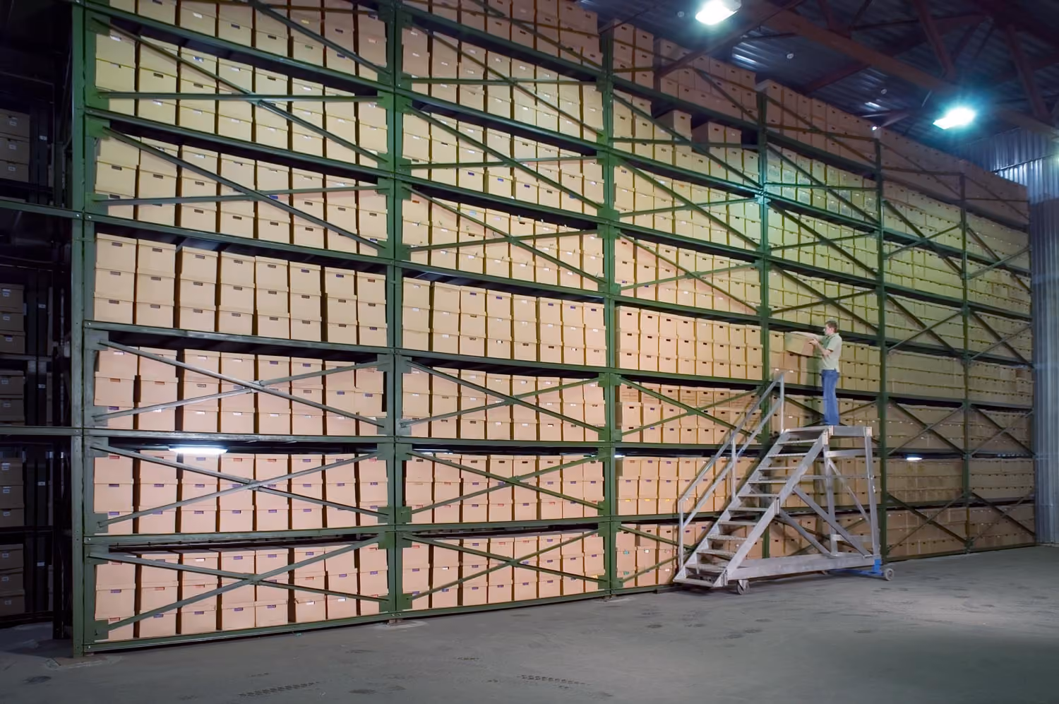 A ladder is in front of a large wall of secure document storage boxes.