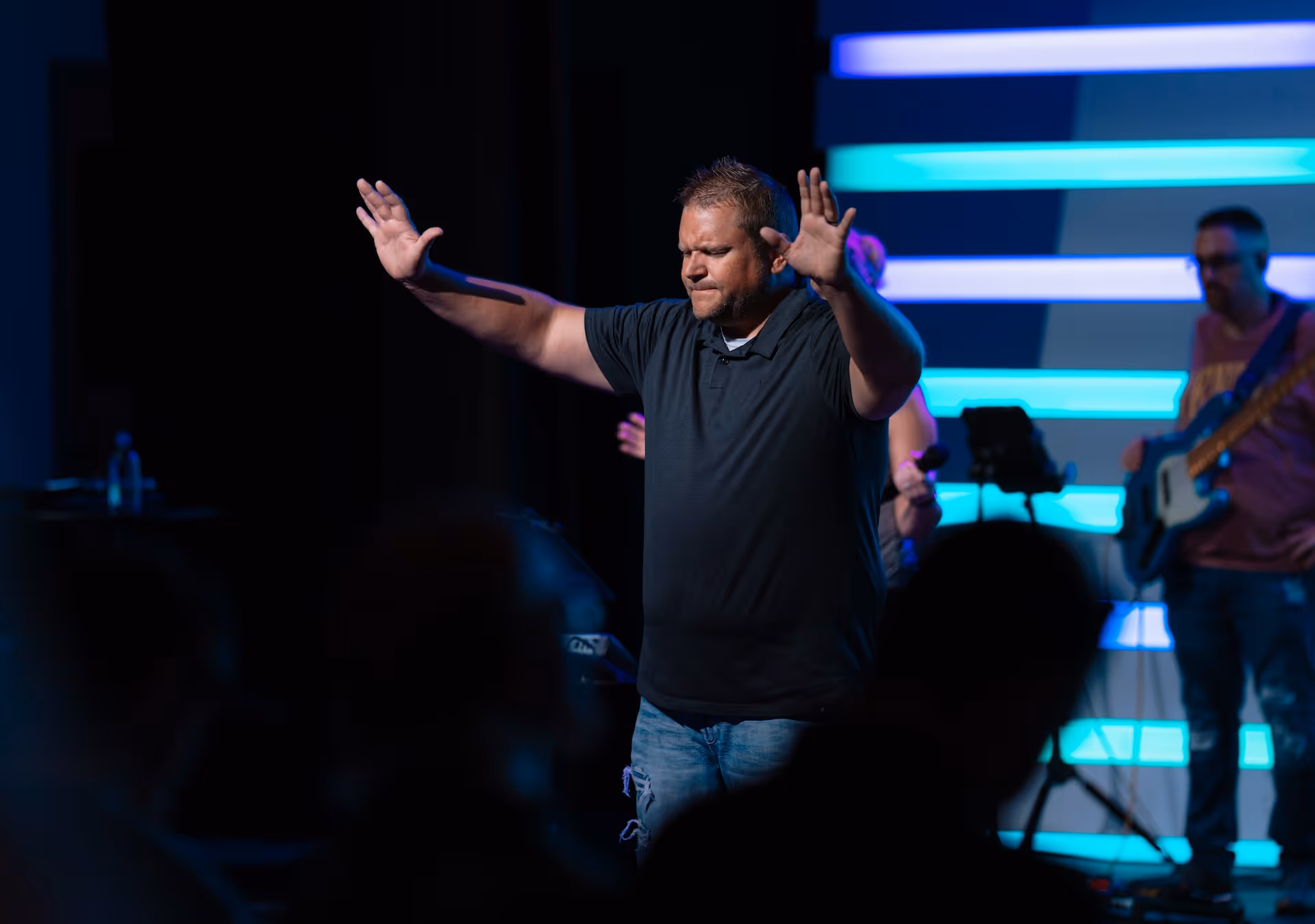 Pastor JP prasing with lifted hands.