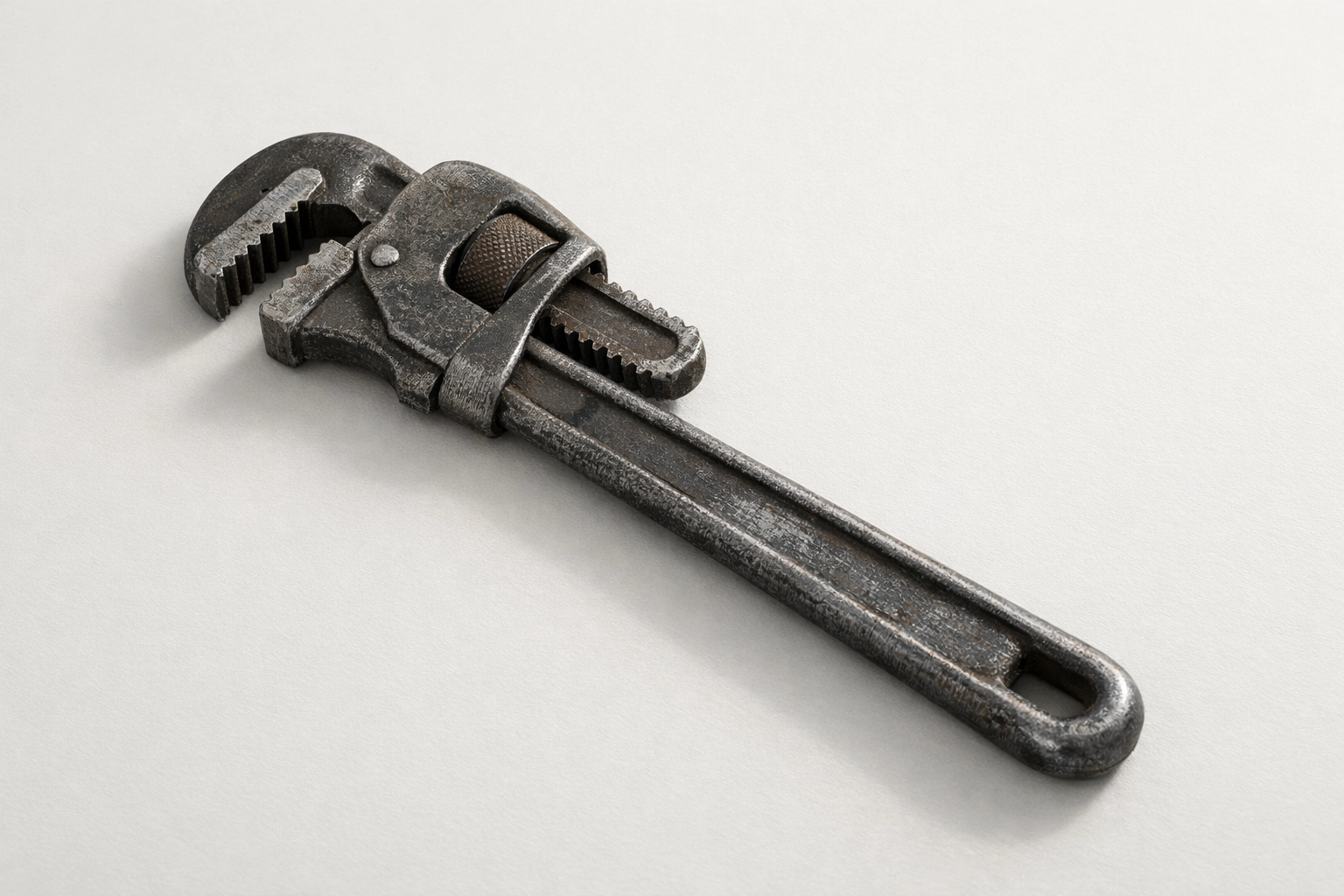 Minimalist photo of a single plumbing wrench on a clean neutral surface