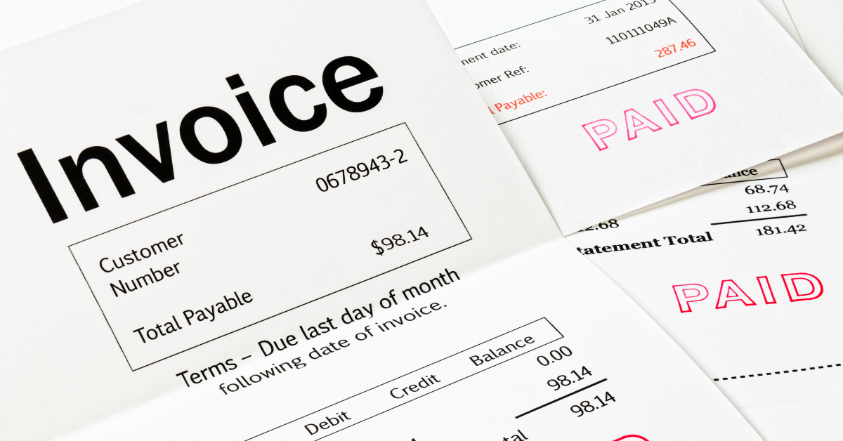 Construction hard hat and invoices on a desk for commercial collection agency services in BC.