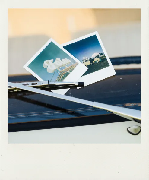 Ein gemachtes Polaroid von zwei Polaroids, die zwischen den Scheibenwischern liegen.