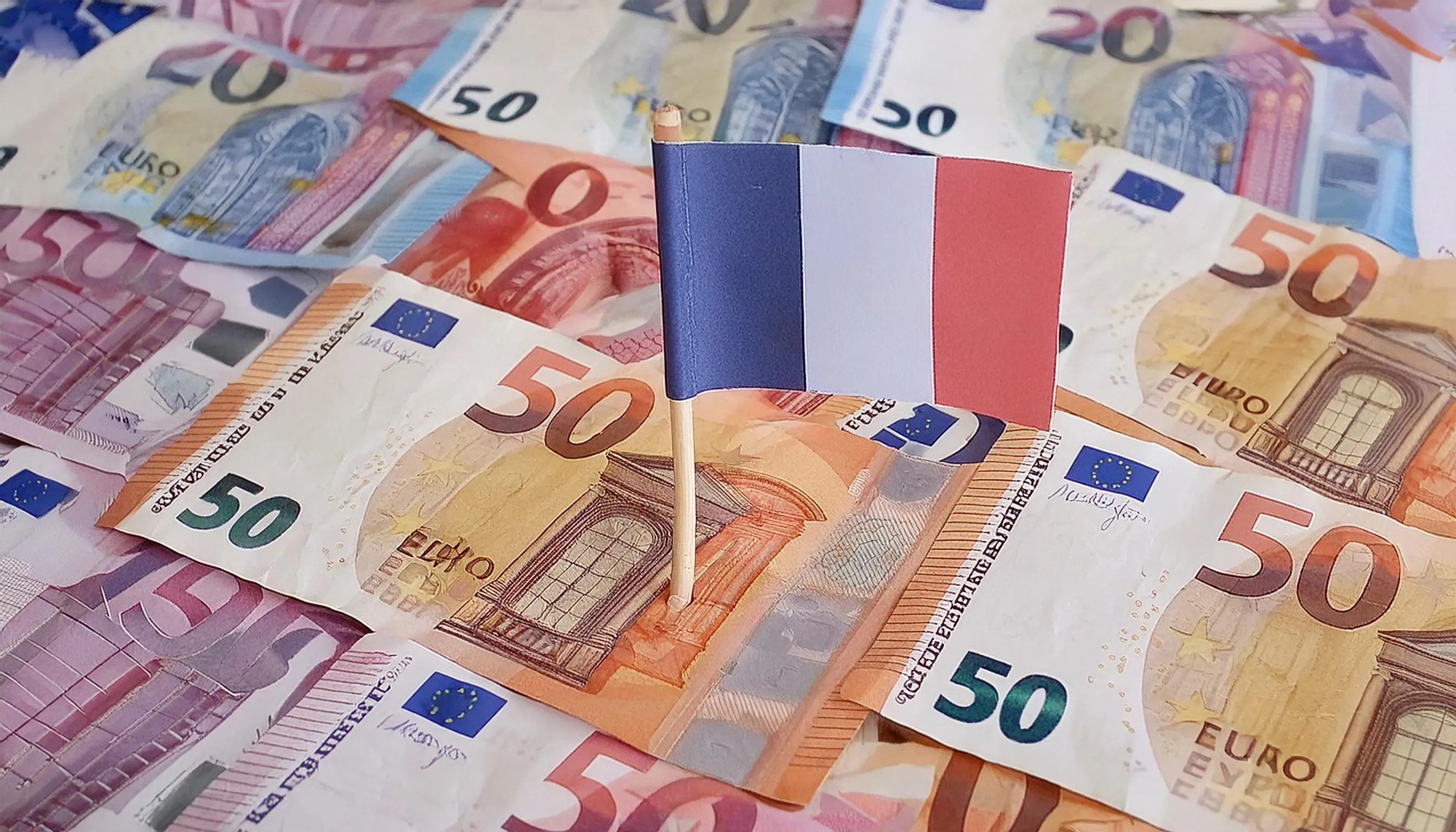 Drapeau français sur des billets d'euros, représentant les régimes fiscaux de l'immobilier locatif en France.