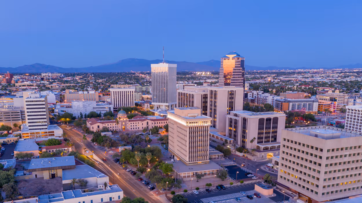 Aerial view of downtown Tucson, Arizona at dusk, showing office buildings and city streets.