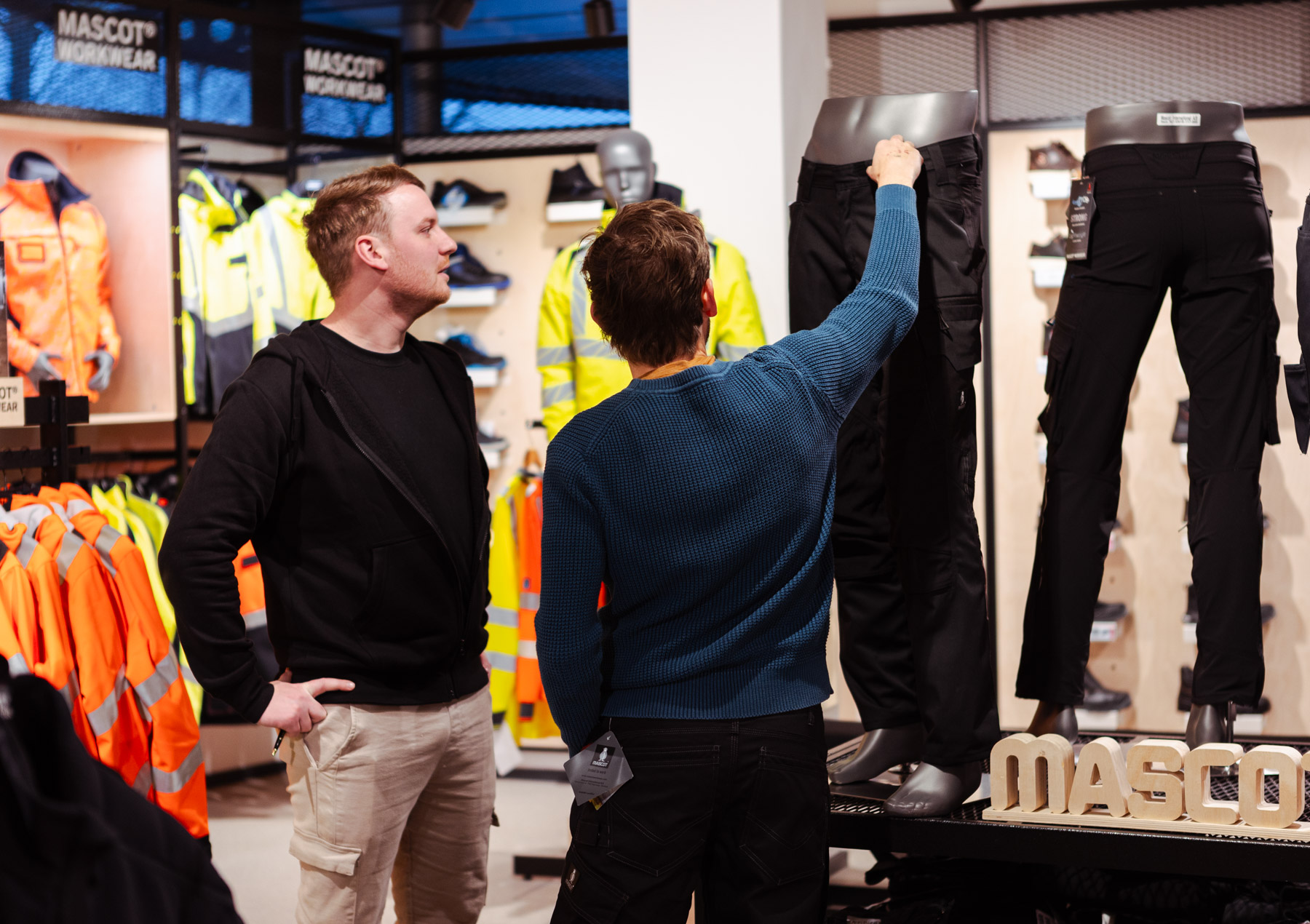 Een medewerker in de winkel van Vermeer Workwear and Safety die een klant helpt om nieuwe werkkleding uit te zoeken.