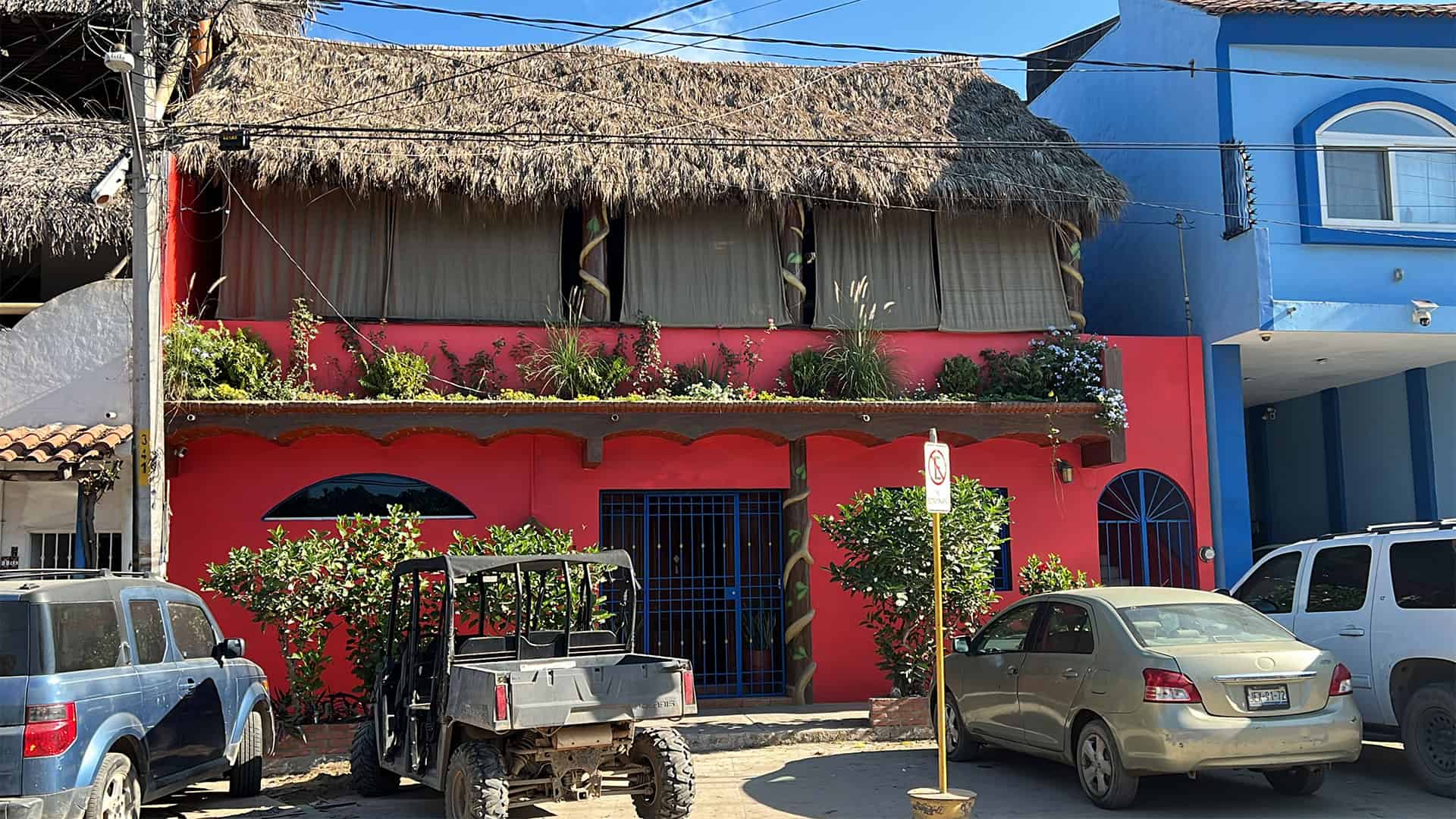 Front of the Casa. A two story building with a palm frond roof.