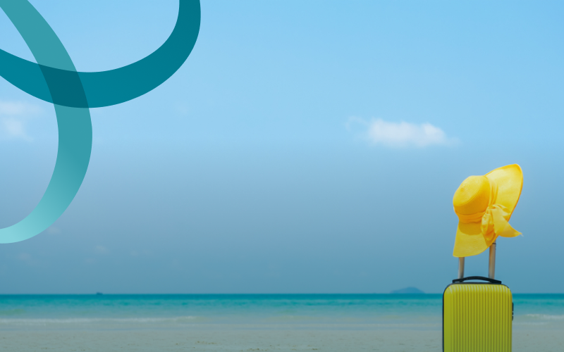 bright yellow luggage and matching hat sits on a pristine beach.
