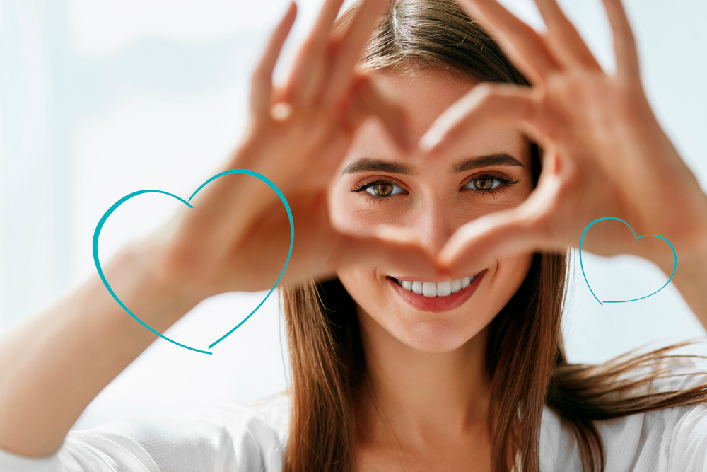 Nurse smiles through a heart made by her hands.