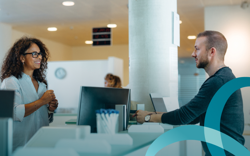 A man approaches the front desk of a health care facility. 