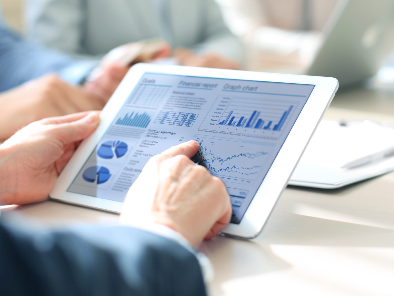 Un investisseur consulte sur une tablette des graphiques financiers et des rapports de performance d’investissement.