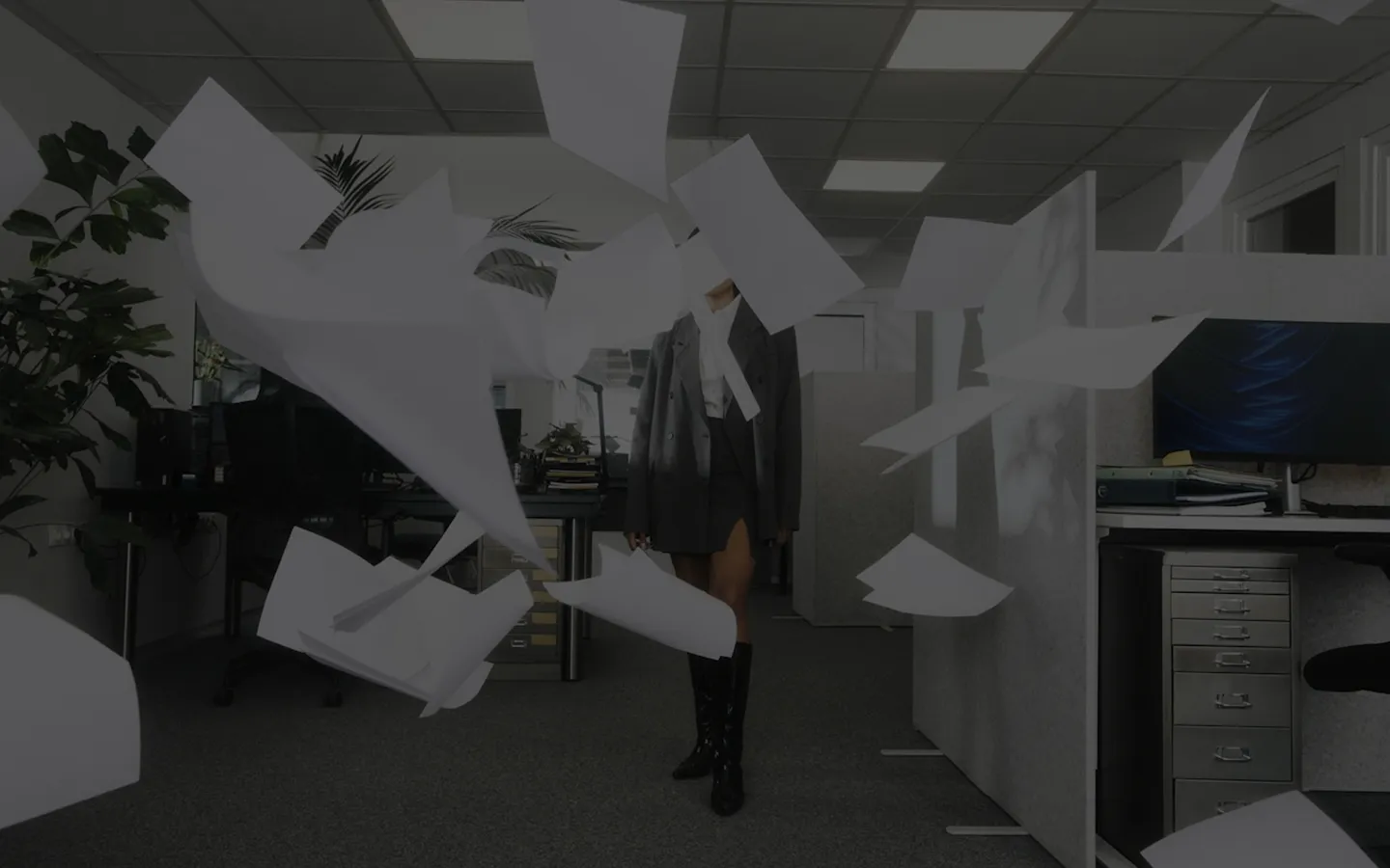 A woman in a suit stands amidst a pile of papers, representing the agency industry and its busy work environment.