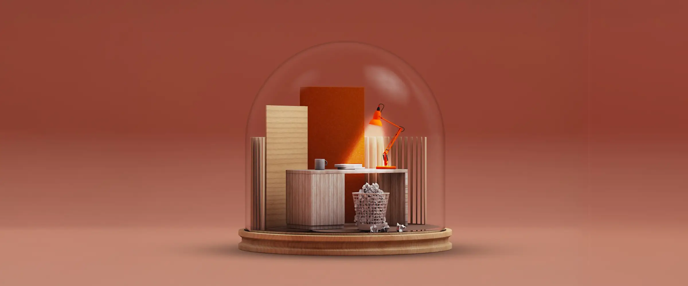 Miniature wooden desk with an orange lamp, books, and a trash bin filled with crumpled paper inside a glass dome on a wooden base.