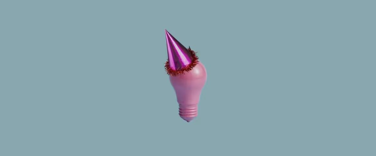 An all-pink lightbulb with a shiny pink party hat propped on top of it.