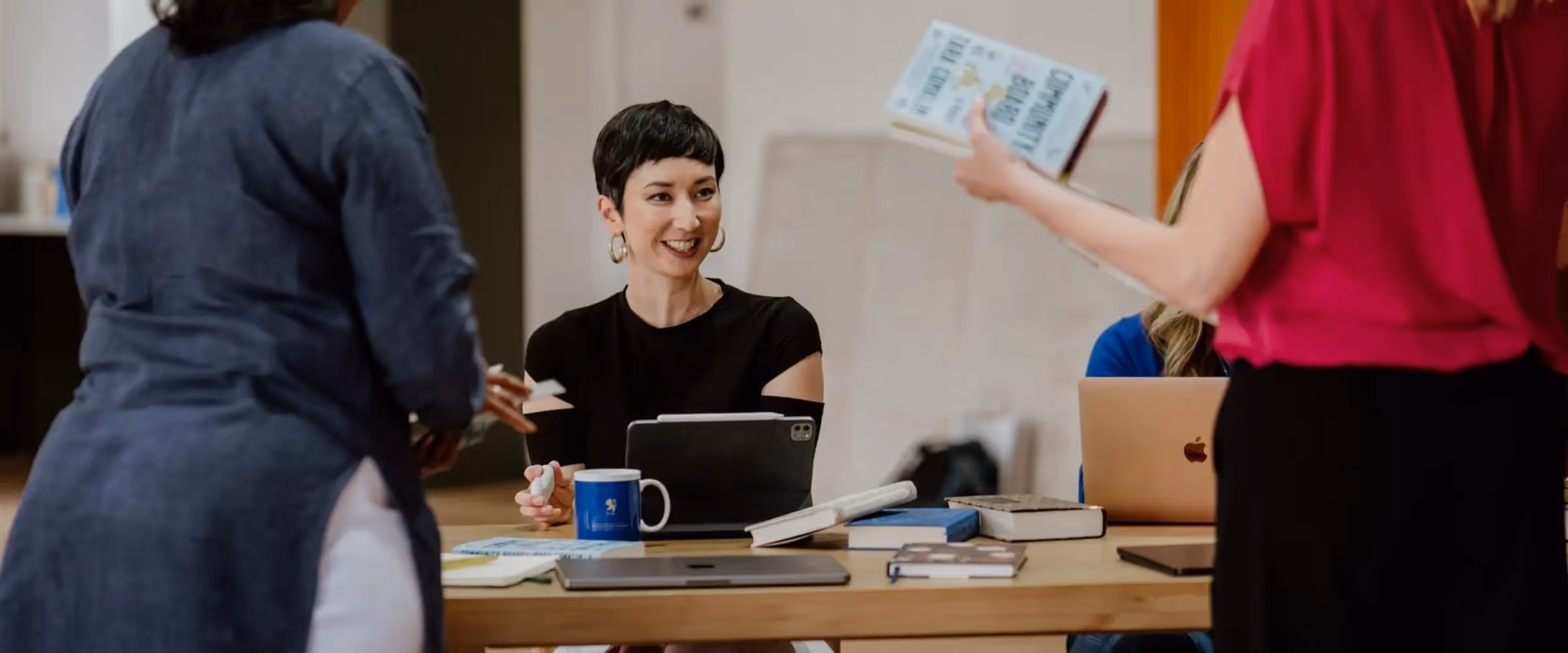 Author and writing coach Andrea Stewart sits at a table surrounded by other writers.