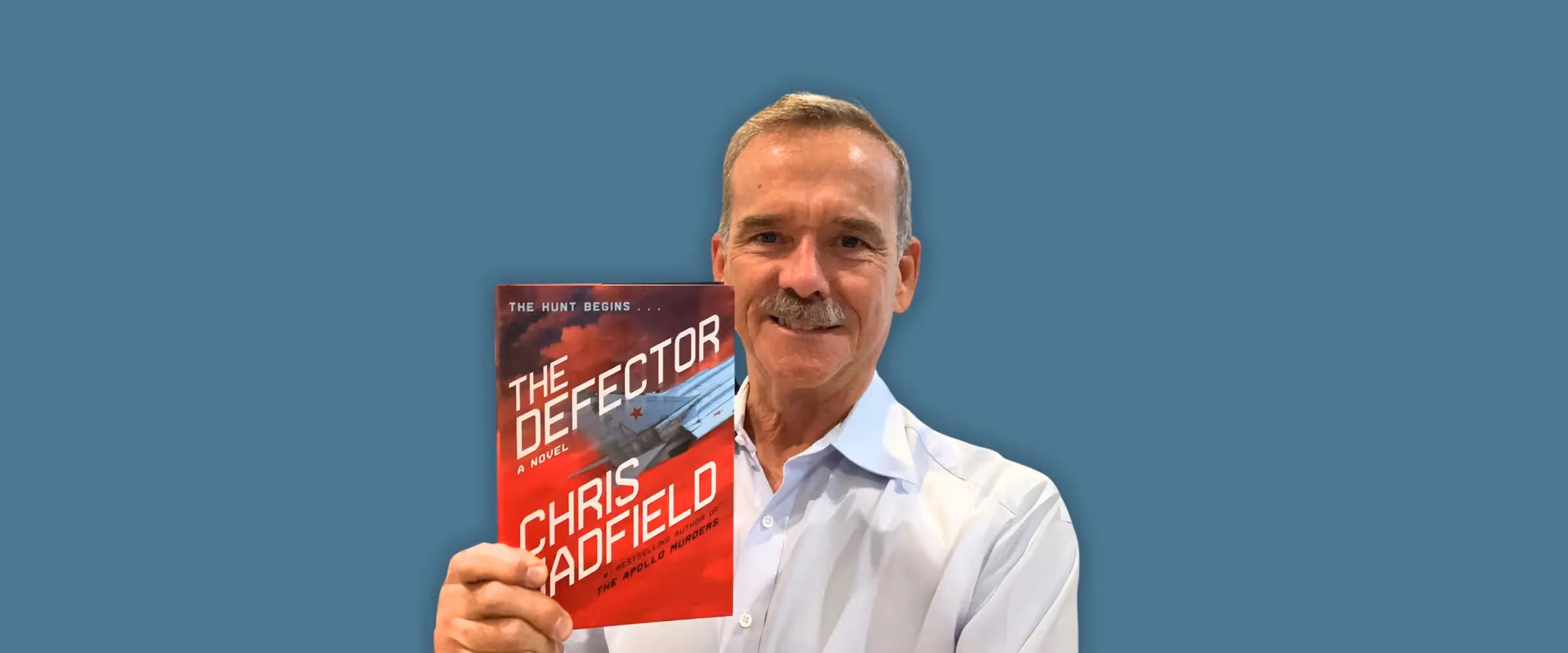 Author and astronaut Chris Hadfield holding a copy of his book, The Defector.